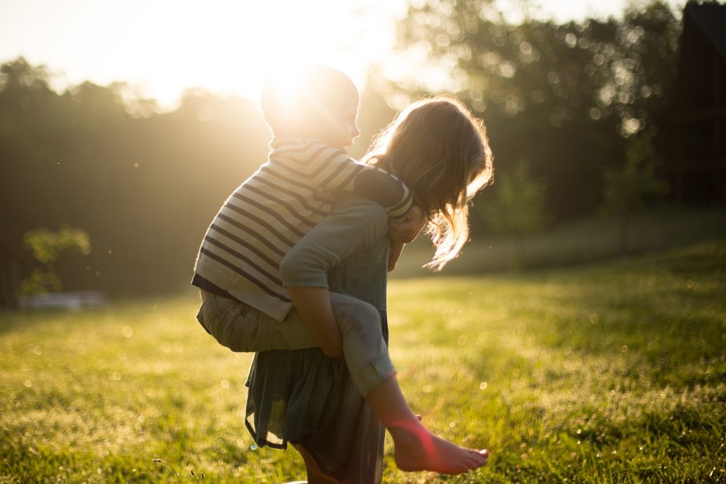Mädchen trägt Junge Huckepack - ©Pexels/Pixabay Ein Mädchen trägt einen kleinen Jungen Huckepack.