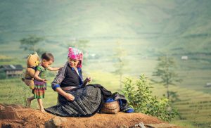 Mutter und ihr Kind - ©sasint/Pixabay Eine Mutter sitzt zusammen mit ihrem Kind auf einem Berg und macht Pause von der Feldarbeit.