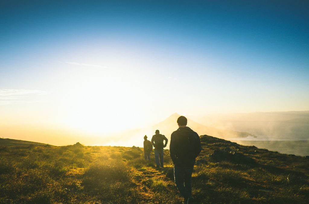 Wanderer im Sonnenuntergang – ©StockSnap/Pixabay Drei Wanderer gehen eine Wanderweg entlang, dem Sonnenuntergang entgegen.